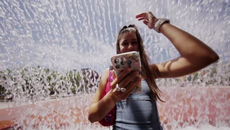 young woman using smartphone by a fountain