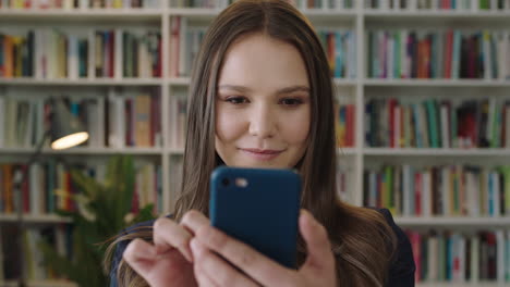 Porträt-Einer-Jungen-Schönen-Frau,-Die-In-Einer-Bibliothek-Steht.-Studentin-Nutzt-Ihr-Smartphone-Und-Lernt,-SMS-In-Sozialen-Medien-Zu-Schreiben