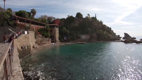 Weite-Schwenkaufnahme-Mit-Blick-Auf-Die-Küstenlinie-Der-Türkischen-Ferienstadt-Antalya,-Heller-Sonniger-Tag-Und-Türkisfarbener-Ozean