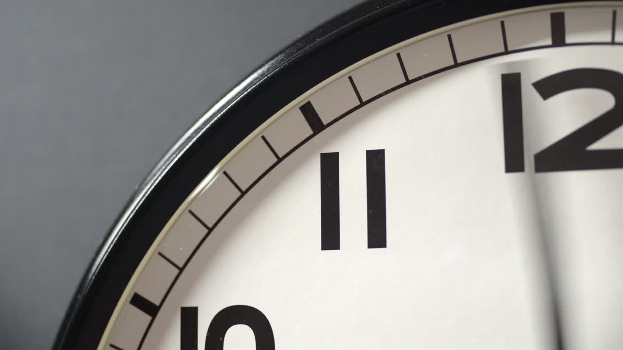White Clock Face Close Up in Time Lapse on Dark Grey Wall