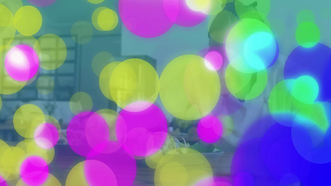 Female chef wearing white coat reaching salad ingredients and tweezing greens onto kitchen platter