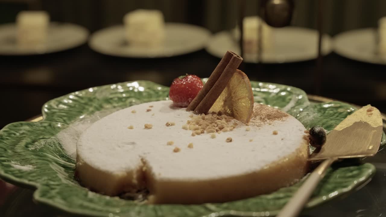 close up of elegant sliced cake with cinnamon and fruit garnish on a green ceramic plate