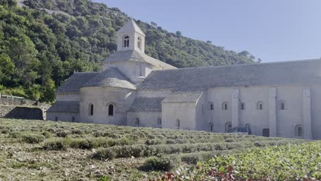 Großes-Kloster-In-Frankreich-Mit-Glockenturm-Und-Steingebäuden-Mit-Kleinen-Hügeln-Im-Hintergrund