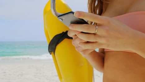 sección media de una mujer usando un teléfono móvil en la playa 4k