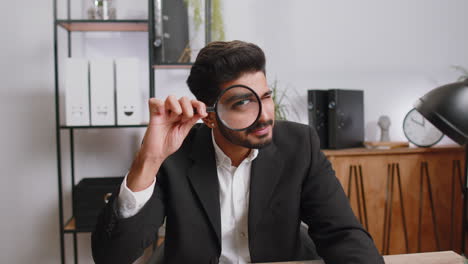 business man holding magnifying glass near face, looking with big zoomed eye, searching, analysing