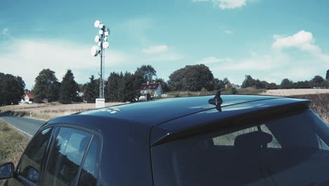 black car with network communication mast for automatic driving and steering of the car in the background