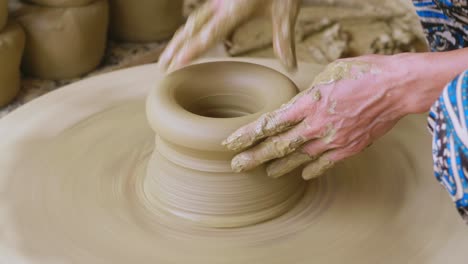 meticulously sculpting clay into pots on a electric wheel