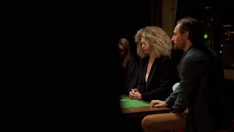 group of friends playing poker sitting on chairs at a table at home 2