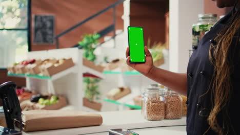 vendedor de la tienda sosteniendo un teléfono con pantalla verde
