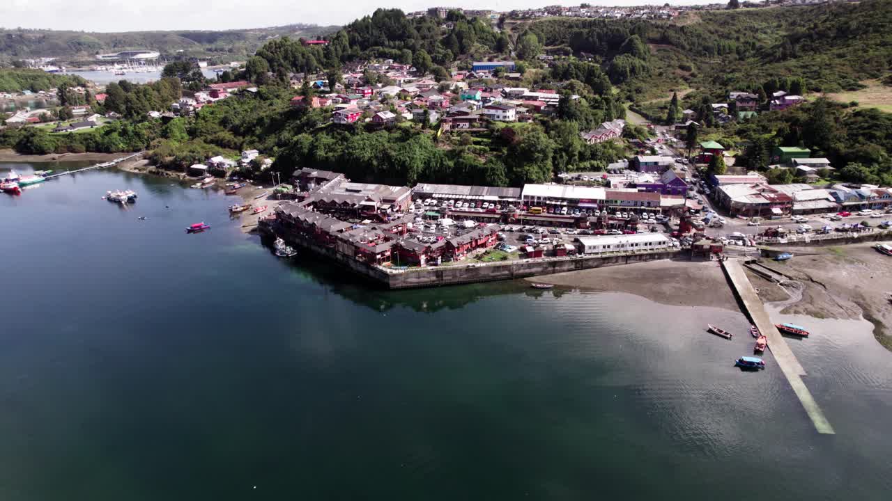 The coastal town of Puerto Montt, Chile, showcasing the bustling waterfront, harbor, and houses nestled in the lush green hills of the Los Lagos region of Patagonia