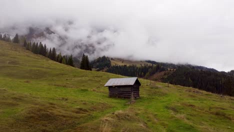 Pequeña-Cabaña-De-Madera-En-Las-Montañas-De-Austria,-El-Retroceso-Aéreo-Revela-El-Paisaje,-Hochkonig