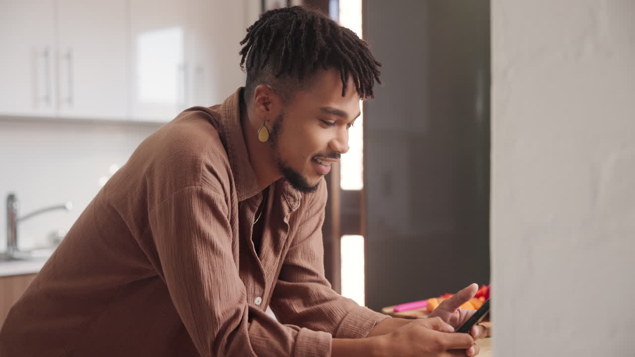 Man using smartphone in kitchen