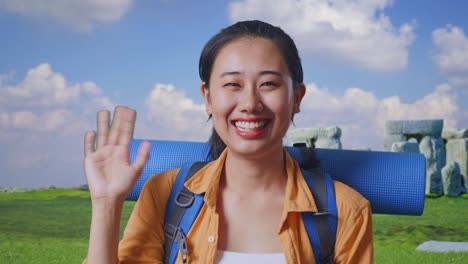 close up of asian female hiker with mountaineering backpack waving hand and saying bye while traveling in stonehenge