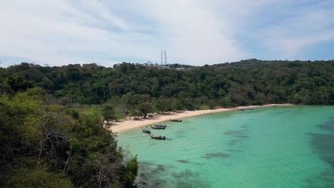 loh moo dee beach in thailand, with turquoise waters, longtail boats, and lush jungle on phi phi don island.