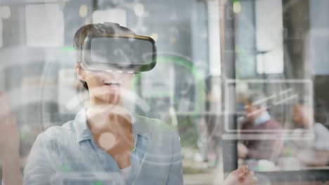 escaneo de alcance sobre iconos digitales contra una mujer de negocios caucásica que usa auriculares vr en la oficina