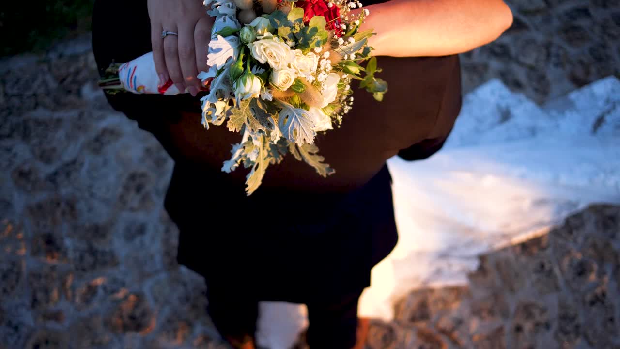 Brudepar holder hinanden i armene med smuk blomsterbuket, ovenfra-optagelse