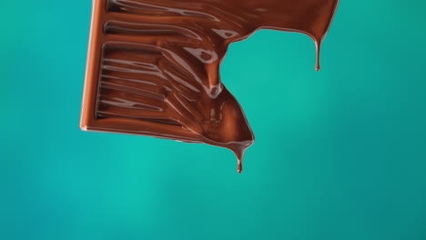 close up of melting chocolate bar against blue coloured background with copy space 2