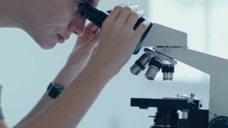 científica de laboratorio que trabaja con el microscopio