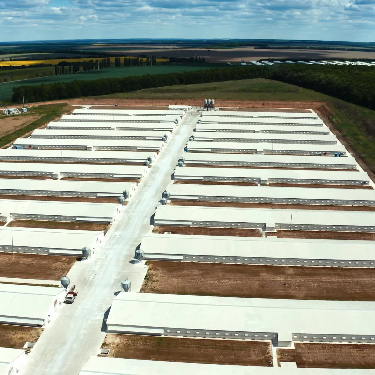 Innovative complex among nature. White roofs of a modern production plant on the field. Exterior of manufacturing. Aerial view.