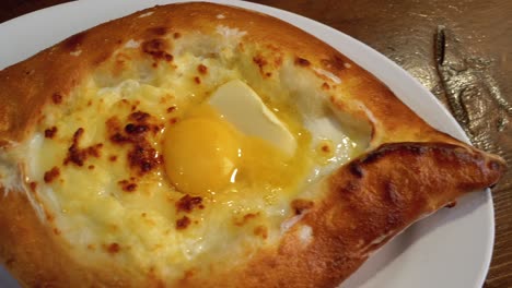 adjarian khachapuri en una mesa en un restaurante georgiano. pastel de pan abierto con yema de huevo