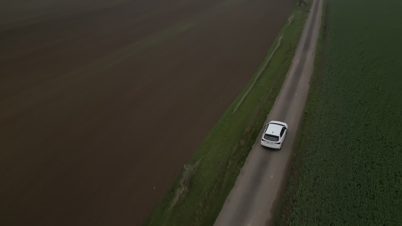 Auto bianca che percorre una strada di campagna, vista con drone, tempo autunnale nuvoloso