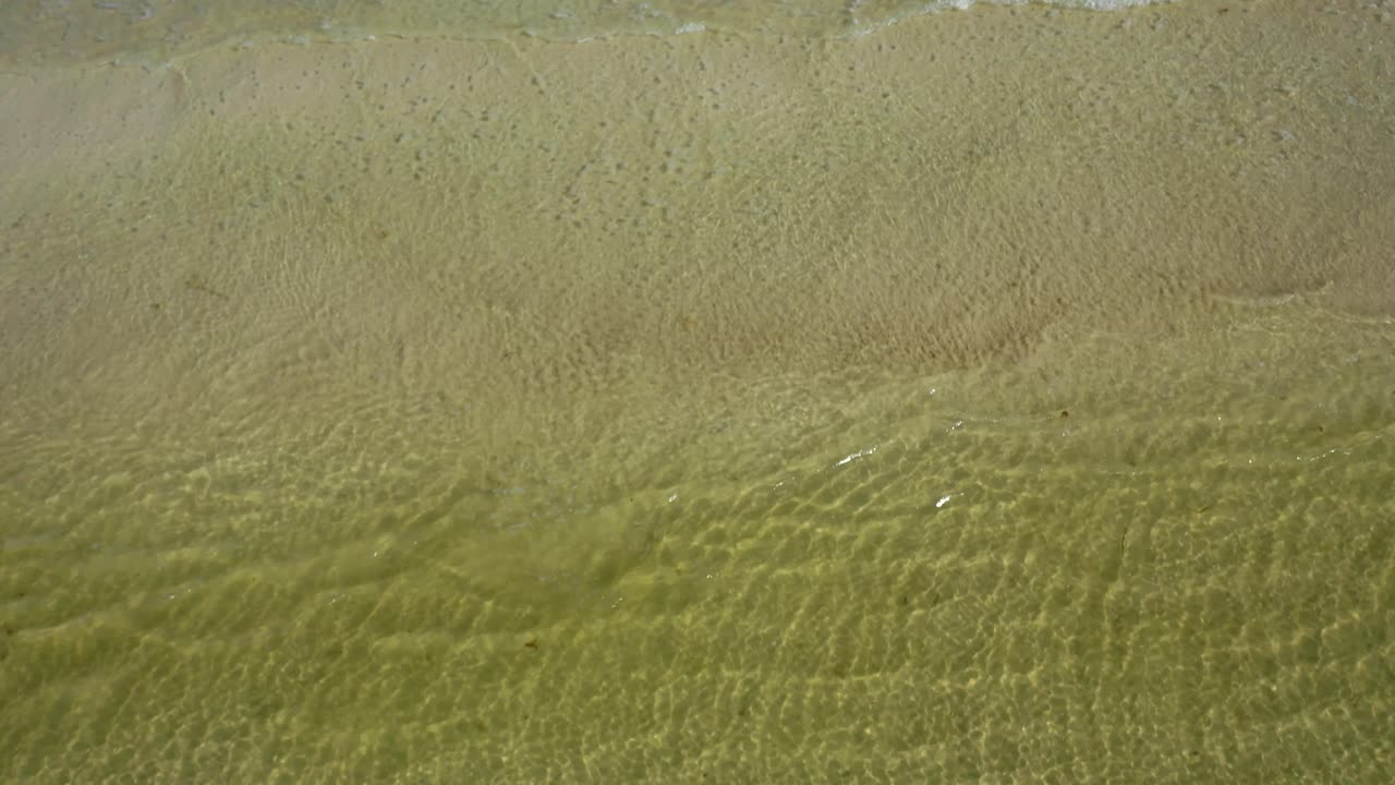 카메라는 해변의 모래에 쓰여진 긴장을 풀기 위해 바다를 보여주는 수평선에서 아래로 기울어집니다.