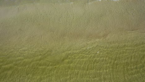 la cámara se inclina hacia abajo desde el horizonte mostrando el mar para relajarse escrito en la arena de una playa