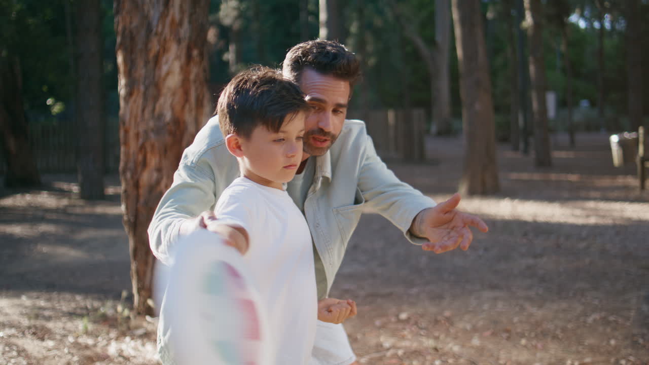 Happy family doing sports in park closeup. Father teaching son throwing frisbee