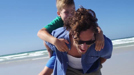 Father-giving-piggyback-ride-to-his-son-at-beach