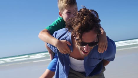 father giving piggyback ride to his son at beach