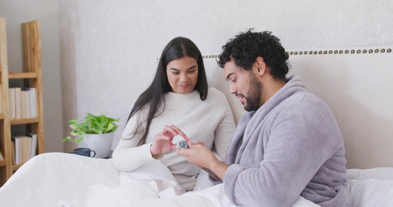 Happy Couple Examining a New Watch Together in Bed