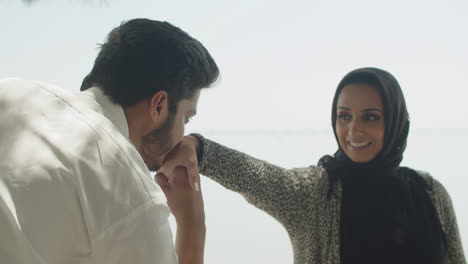 handsome muslim man kissing hand of smiling lady in hijab.