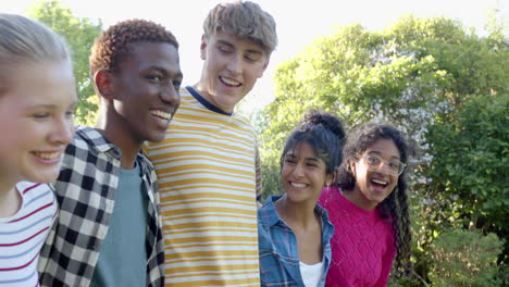 un grupo feliz y diverso de amigos adolescentes abrazándose en un parque soleado, en cámara lenta