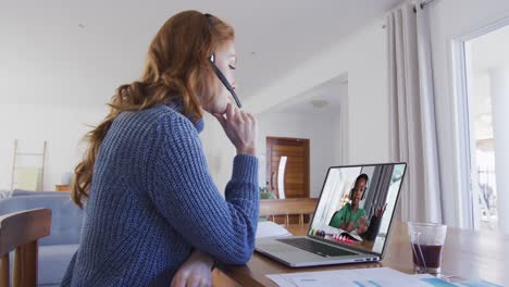 maestra caucásica sentada en un escritorio usando una computadora portátil teniendo una lección escolar en línea