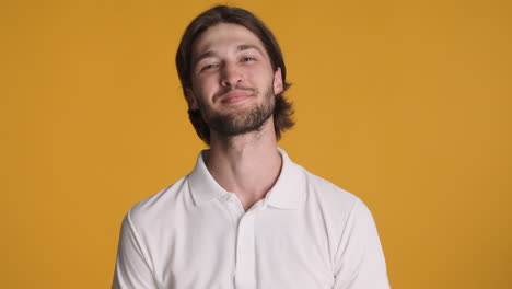 caucasian man waving at camera on yellow background.