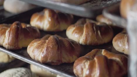 close-up of multiple trays filled with assorted baked pastries cooling on racks inside a bakery