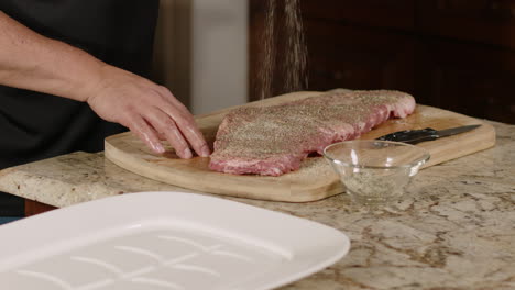 costillas de cerdo crudas siendo sazonadas con especias en cámara lenta