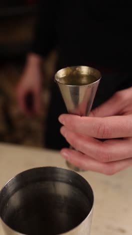 bartender pouring liquor into a cocktail shaker