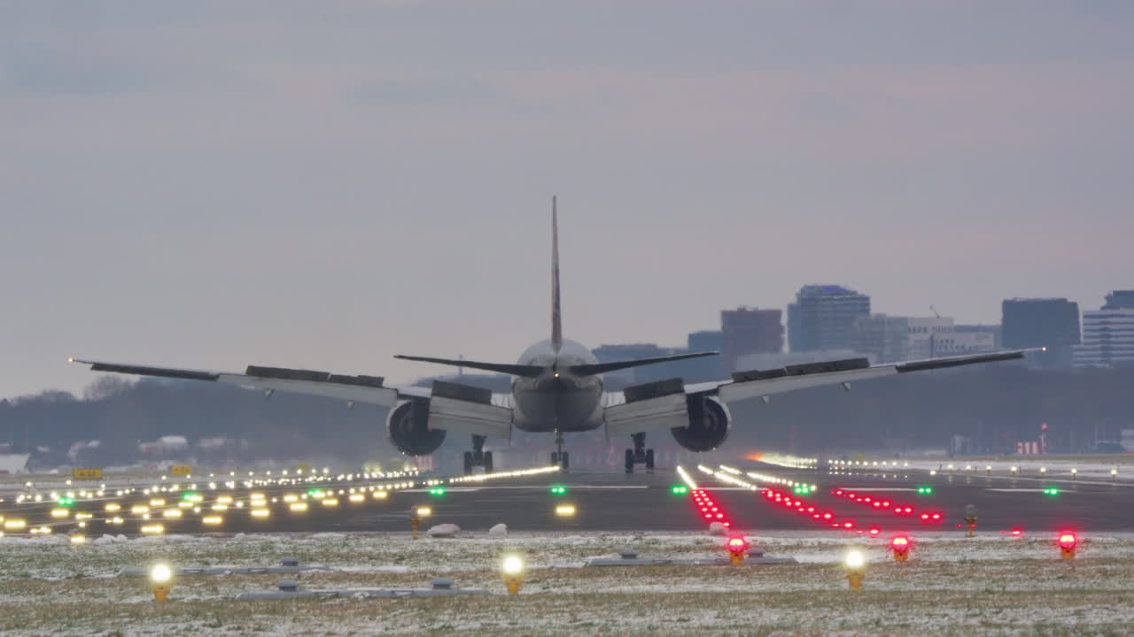 Grande aereo passeggeri in atterraggio su pista illuminata al crepuscolo.