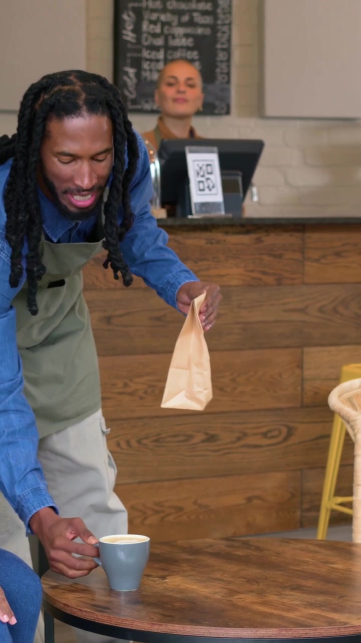 Vertical video: Server entering placing cup folding bag at counter staff watching smiling for guest