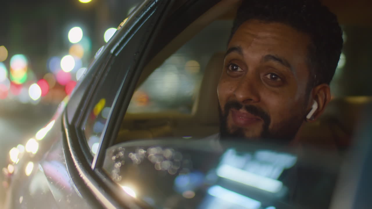Businessman in Earphones Riding in Car in Night City