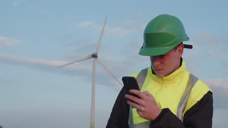 el joven ingeniero comprueba los datos de rendimiento de la turbina eólica en su teléfono móvil