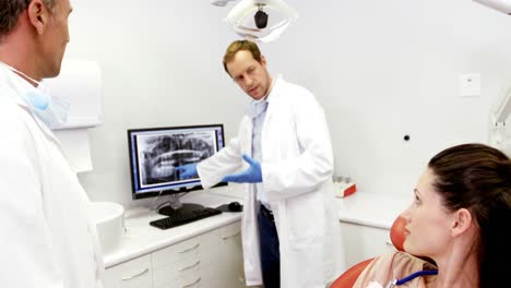 dentist showing an x-ray of teeth to female patient on computer