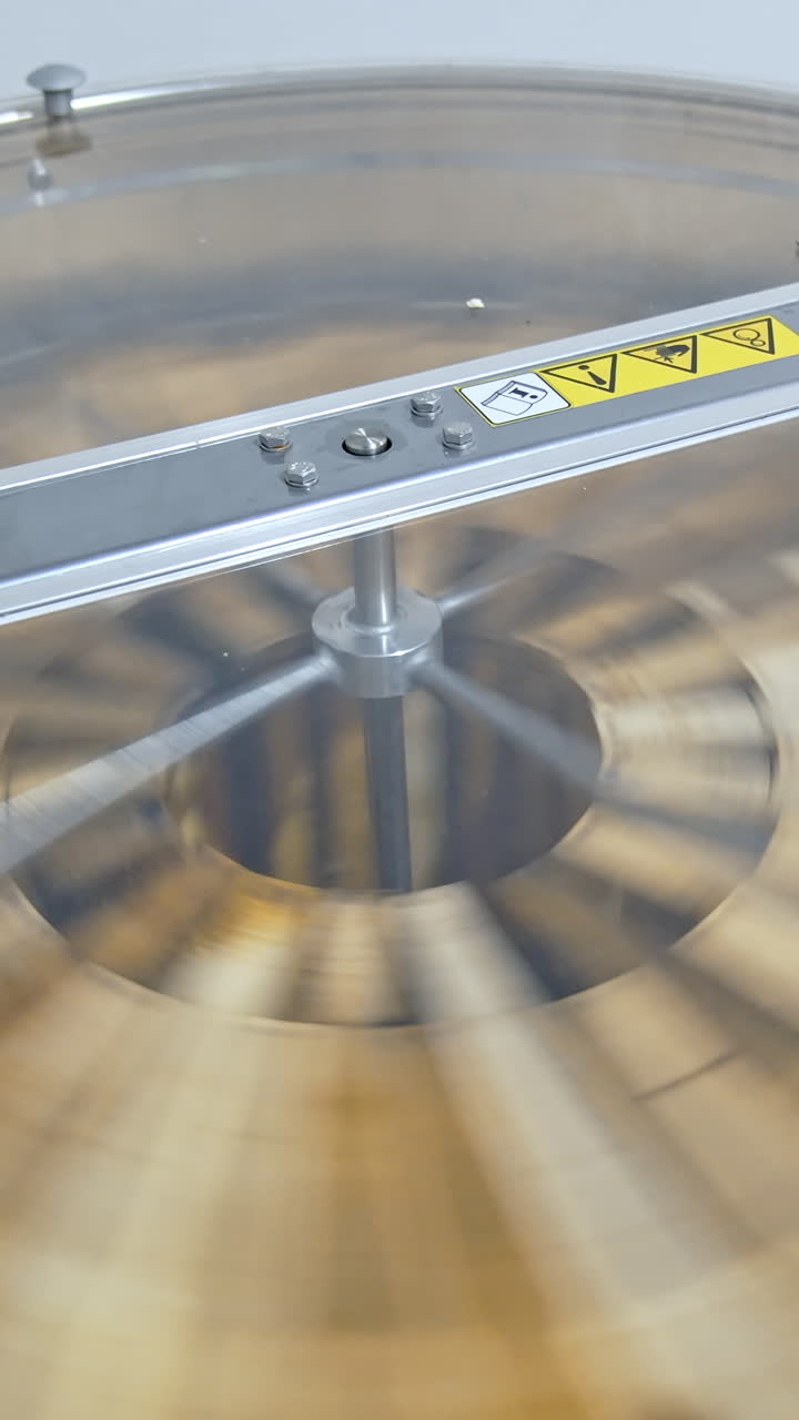 Beekeeping technology for making fresh honey from honeycomb. Honey extractor machine working. Centrifuge with frames spinning. Honey production. Vertical video