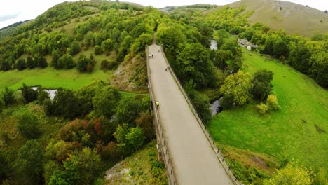 descending aerial view cyclists and hikers crossing headstone viaduct, bridge in the derbyshire peak district national park, bakewell