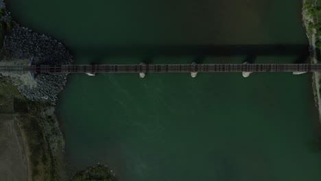 Bird's-eye-view-aerial-shot-of-a-scenic-train-bridge-and-mountain-river