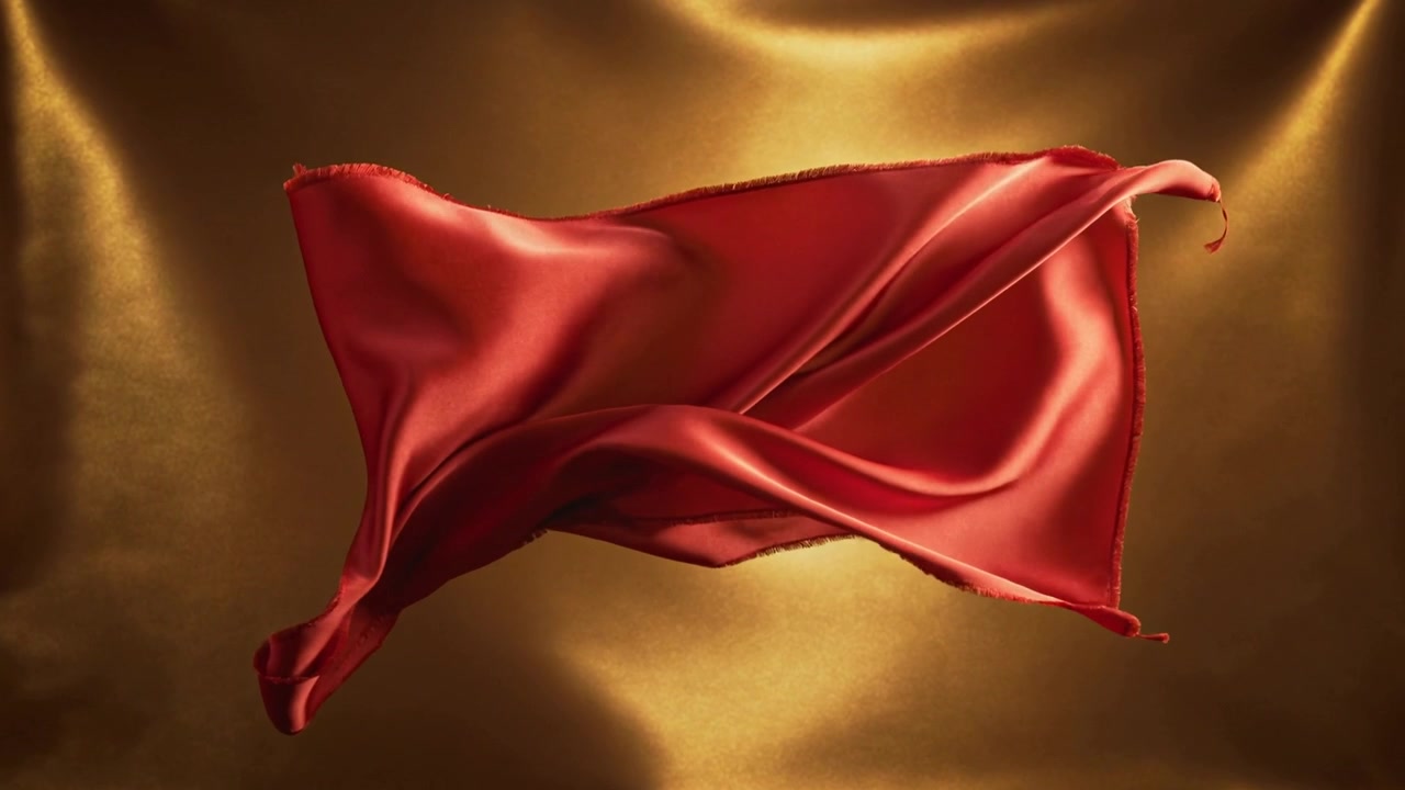 Floating red silk cloth unfurling in studio gold backdrop, lit by lights, fan-driven for showcase