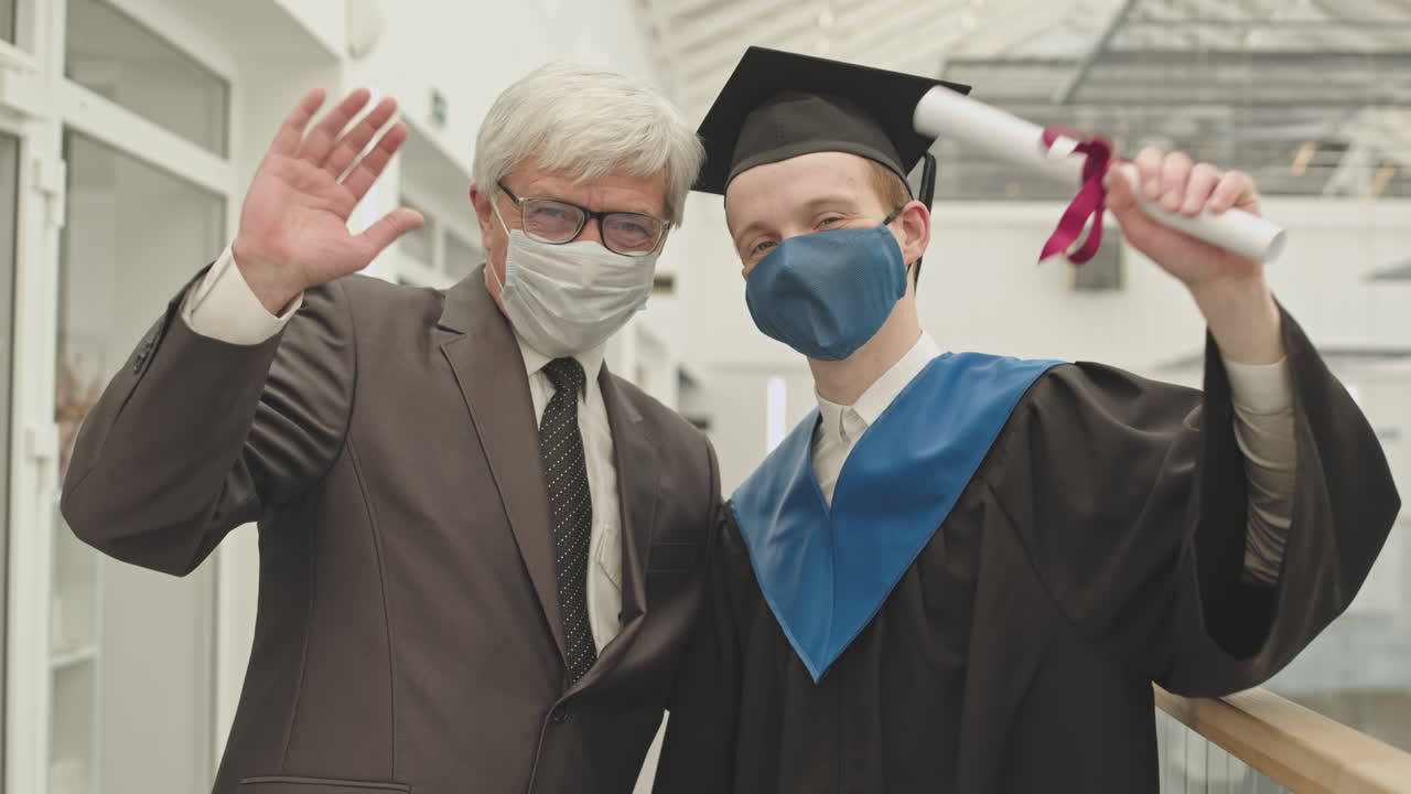 Senior University Tutor Congratulating Male Graduate