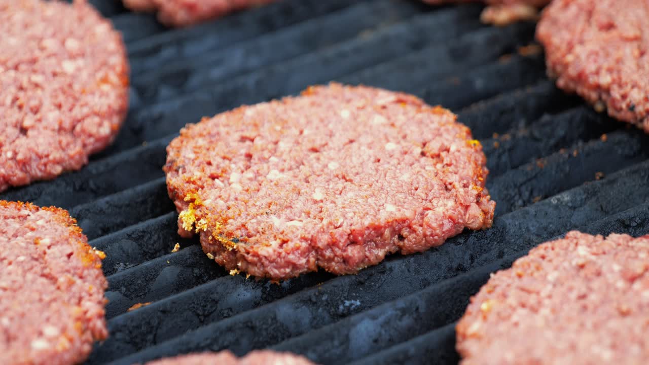 Barbecuing plant based Impossible Burger patties on electric grill close shot panning down quickly over uncooked patties freshly placed on the grill - in Cinema 4k (30fps slow from 60fps).
