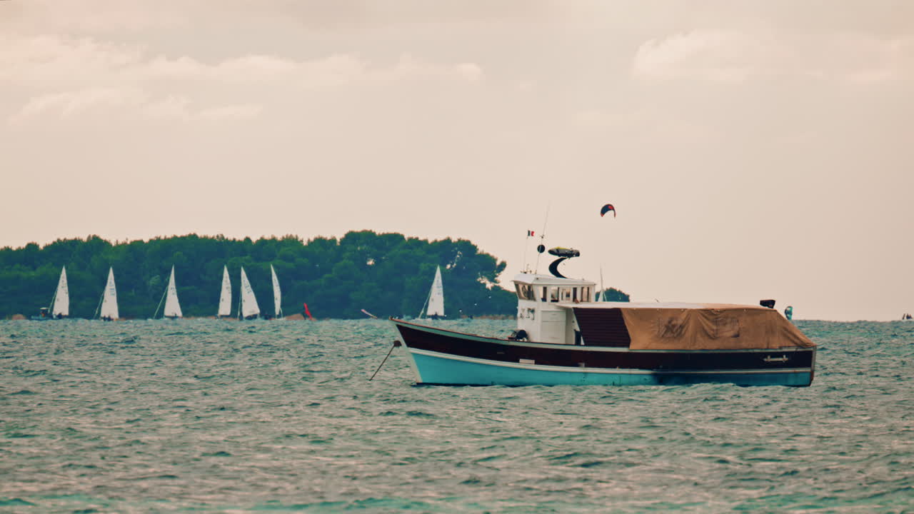 A traditional wooden work boat with a canvas cover floating on turquoise Mediterranean water